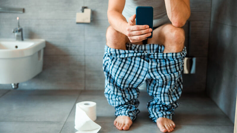 Prostataentzündung (Prostatitis): Ein Mann mit ständigem Harndrang sitzt auf der Toilette. 