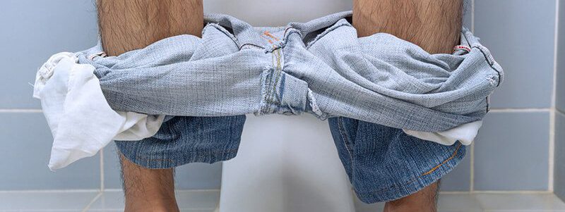 Ständiger Harndrang: Mann sitzt mit Problemen beim Wasserlassen auf Toilette